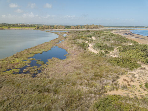 Swampy isthmus, saline lake with an observation hut and the Mediterranean Sea, Riserva naturale di Vendicari, Sicily, Italy, drone photo