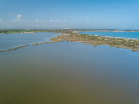 Saline lake Pantano Sichilli with two swans on water, Mediterranean Sea, Riserva naturale di Vendicari, Sicily, Italy, drone photo

