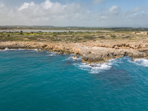 Rocky coast and blue Mediterranean Sea, sunny day, Riserva naturale di Vendicari, Sicily, Italy, drone photo

