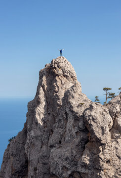 A man reaches the mountain peak with his arms outstretched