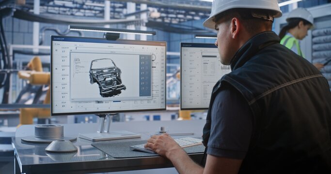 Technician Controls Robotic Arm Factory Operations Using CAD Software and Analytics on Monitor. Industry 4.0 Technology Drives Efficiency in Modern Automated Vehicle Assembly. AI Manufacturing.