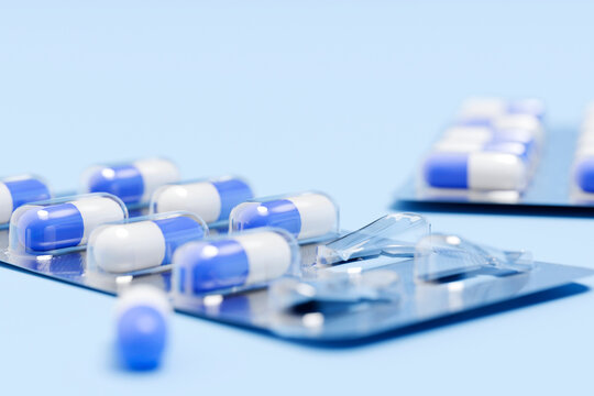 Blue and white capsules sit in blister packs on a blue background