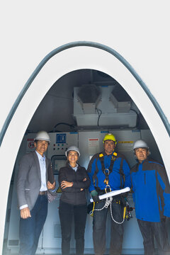 Coworkers stand inside a wind turbine base looking at the camera