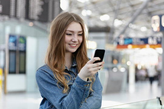 Germany, Cologne, Teenage girl holding mobile at airport