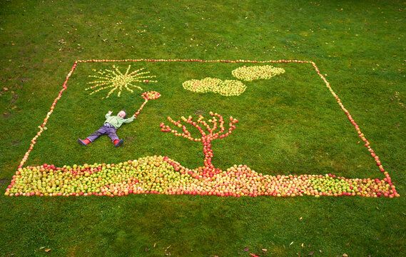 Germany, Boy lying on apples framing picture