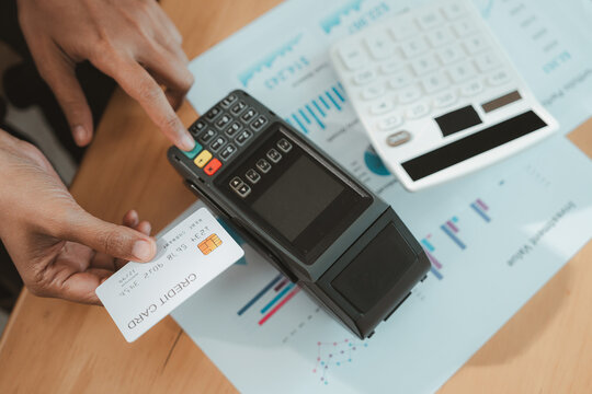 Financial advisor uses payment terminal for wealth planning with bank card and business report at desk, supporting secure transaction analysis and professional financial service