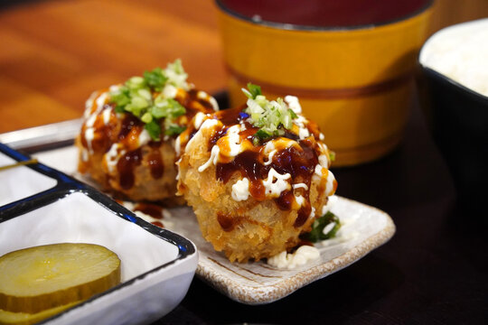 Crispy Japanese Menchi Katsu meat cutlet balls with savory brown sauce and mayonnaise toppings close up
