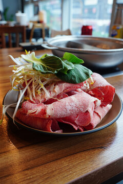 Fresh raw sliced beef for shabu shabu hot pot with bean sprouts and bok choy on a plate