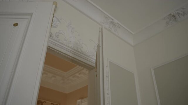 Progressive opening of ornate white double doors revealing decorative plaster crown molding and adjoining warm beige room, with door, opening, molding, plaster detail