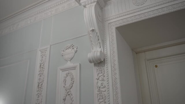 Ornate classical doorway and wall paneling with carved pilaster and Greek key molding in muted pastel interior, with architecture, interior, molding, ornament detail