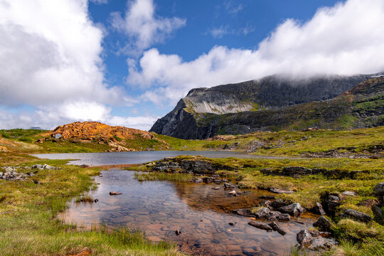 A small mountain lake near the orange rock formations. A summer landscape of a protected nature reserve Kallskaret in World Heritage Area in Western Norway.