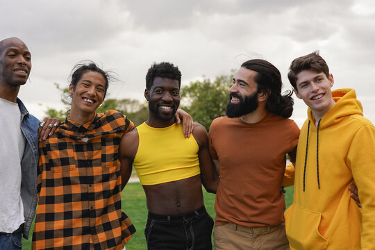 Group of multiracial men hugging each other at city park - Diverse ethnic male friends having fun together outdoor - Diversity, social inclusion and young people lifestyle concept