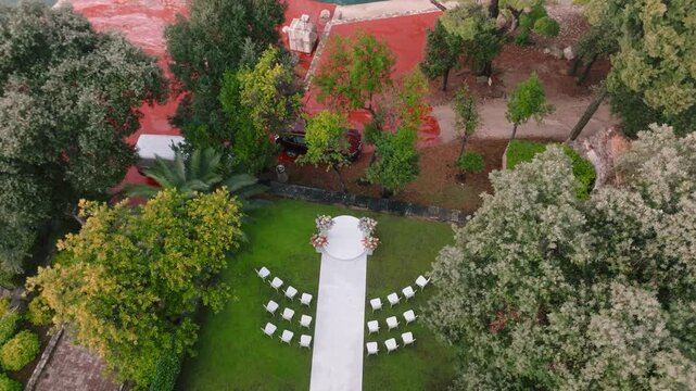 Aerial view of a wedding ceremony setup with white chairs and a walkway on a green lawn surrounded by trees on the island of Sveti Andrija in Rovinj, Istria County, Croatia.