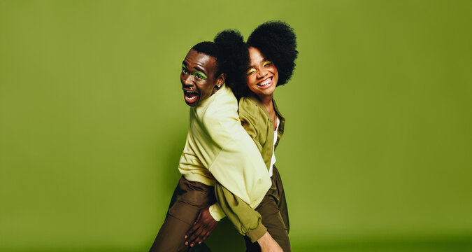 Smiling friends dance together back to back in the studio with playful energy