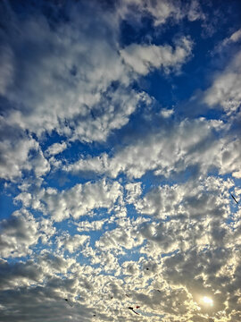 Scenic Blue Sky Filled with White Clouds and Sun Flare