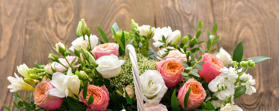 Beautiful bouquet of bright flowers in basket. Basket with roses.  Fowers over wooden background.