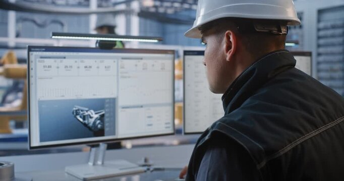 Industrial Engineer Types on Keyboard, Inspecting CAD Car Chassis Model on Desktop Display at High Tech Facility. Robotics Integration Drives Modern Smart Factory Digital Transition. AI Manufacturing.