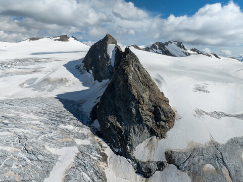 Aerial view of Ghiacciaio del Rutor featuring rugged rocky peaks and vast expanses of snow and glacial ice under a bright sky in La Thuile, Aosta Valley, Italy.
