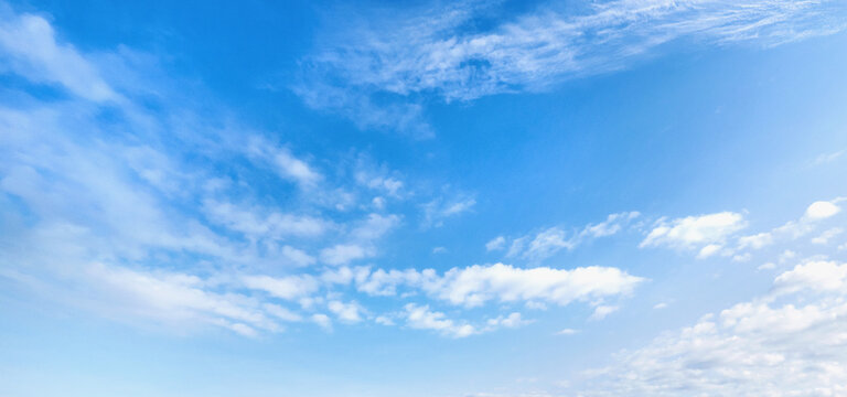 Clear blue sky with wispy white clouds drifting above