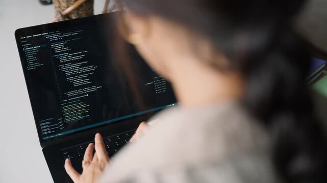 Female programmer writing code on laptop computer