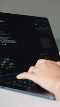 Female programmer's hands typing code on laptop keyboard