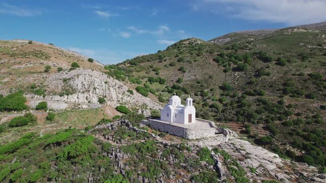 Aerial drone view of Prophet Elias whitewashed church atop Naxos mountain overlooking Filoti village. Isolated sunny Aegean island scenery in Greece by 4k aerial drone