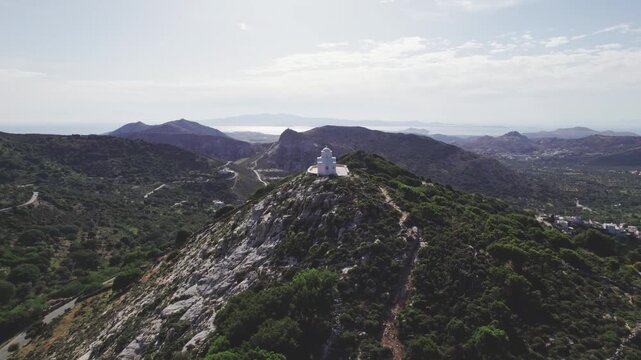 Aerial drone 4k flyover of Prophet Elias chapel on Naxos peak, Greece. Whitewashed Cycladic dome against dramatic rocky crags and mountain slopes.