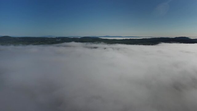 Aerial view of thick morning fog covering the rolling hills and countryside near Pienza, Tuscany, Italy.