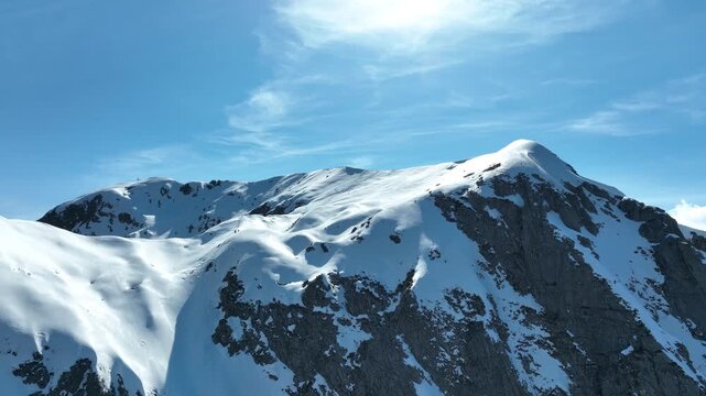 Aerial view of the snow-covered Pania della Croce mountain peak with rocky ridges under a clear blue sky in Stazzema, Tuscany, Italy.