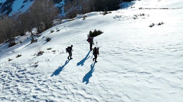 Aerial view of hikers trekking through deep snow on the slopes of Pania della Croce in Stazzema, Tuscany, Italy.