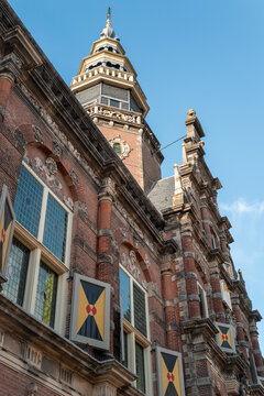 Old building with a tall tower and colorful banners in the clear sky