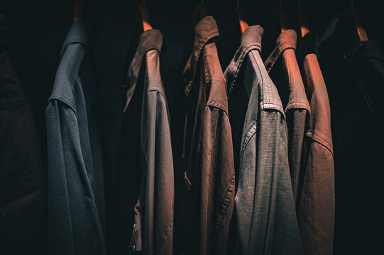 a row of dark jackets hanging neatly on wooden hangers in a wardrobe