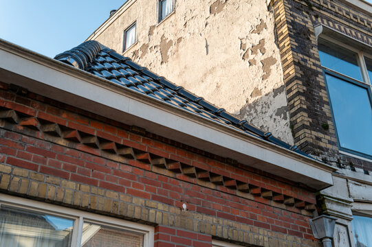 Roof and wall of building with peeling paint show signs of age in urban setting