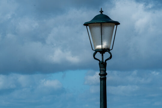Lamp post stands against cloudy sky at a waterfront location during daytime