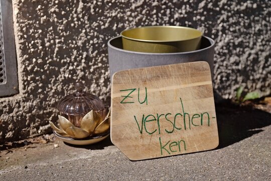 Wooden board with german inscription "zu verschenken" meaning Fee Stuff is lying on the sidewalk