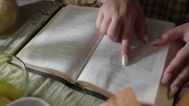 young conservative asian Woman Reading the Bible at table with bread food and drink indoors	
