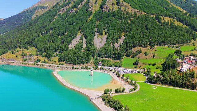 Lake Resia aerial drone famous  peninsula surrounding the iconic flooded church steeple in South Tyrol, Italian Alps