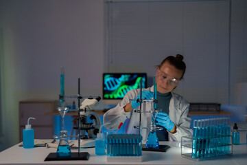 Female scientist conducting DNA research and biotechnology experiments in a dark laboratory,...