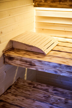 Wooden sauna benches with headrest inside warm steam room interior