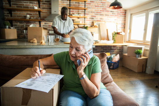 Senior woman reviews moving paperwork on phone at home