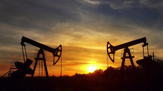 View of oil pumpjacks operating in an oil field during a vibrant sunset in Russia.
