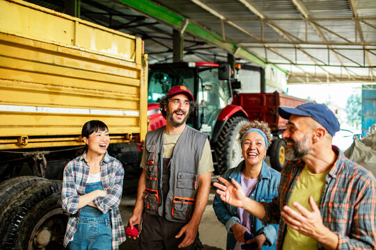 Group of farm workers laughing in tractor shed