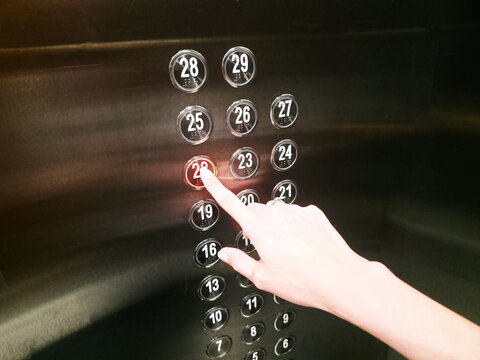 Finger pressing number 28 button in elevator panel