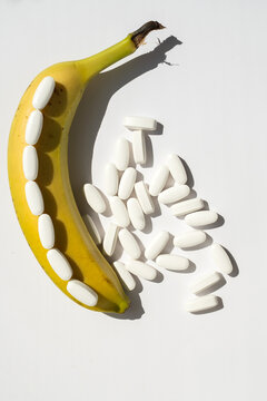 Ripe banana and white pills isolated on white background for men health potency and supplement concept