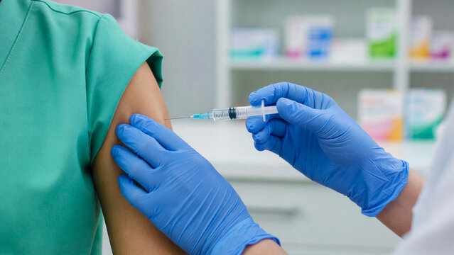 Doctor giving flu vaccine injection to patient arm in clinic, influenza immunization and seasonal disease prevention