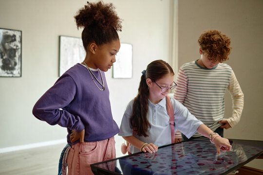 Diverse children looking at interactive screen in art gallery during school field trip. Image represents modern education and interactive learning, perfect for museum marketing
