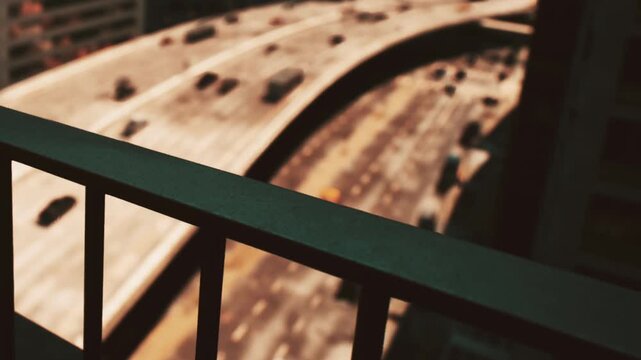 A highway with many cars driving. It is taken from the perspective of a balcony railing. The setting appears to be a city during daytime.