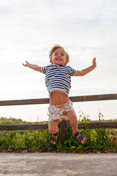 Happy young boy jumping high, enjoying pure childhood joy, freedom, and energy outdoors with a big smile