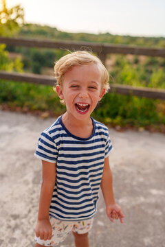 Young boy laughing with pure joy outdoors, celebrating childhood happiness in golden light