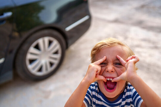 Young boy making funny face, pulling eyelids and mouth, showing playful humor and childhood fun outdoors